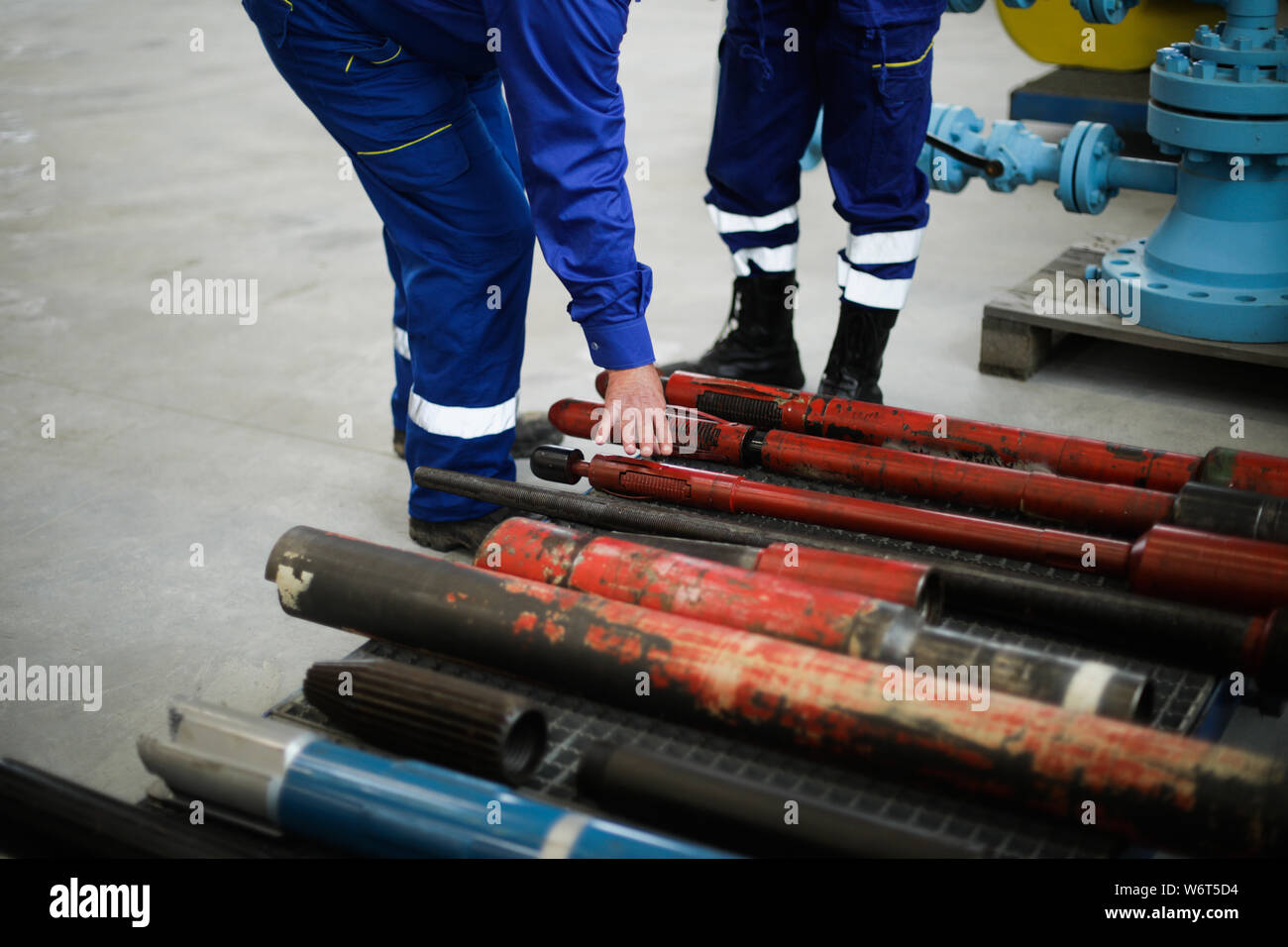 Details with the hands of a worker touching old and rusty heavy iron drilling equipment used in the oil and gas industry Stock Photo