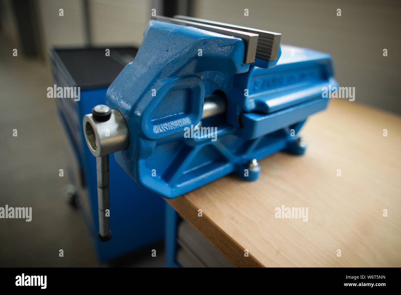 Shallow depth of field image with a heavy iron vice on a workbench inside a workshop with no people around Stock Photo