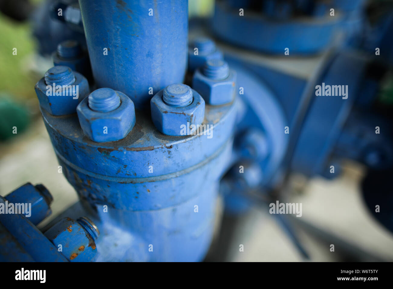 Shallow depth of field image with worn out heavy iron industrial equipment used in the oil and gas drilling industry (rusty bolts, nuts, pipes, levers Stock Photo