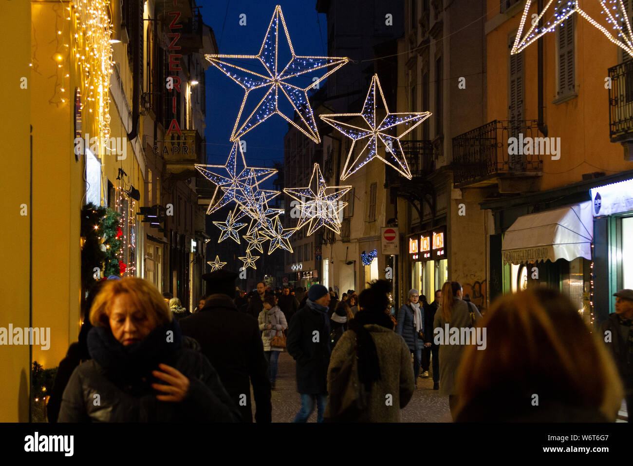 People walking along a street decorated with glittering stars just before Christmas. Stock Photo