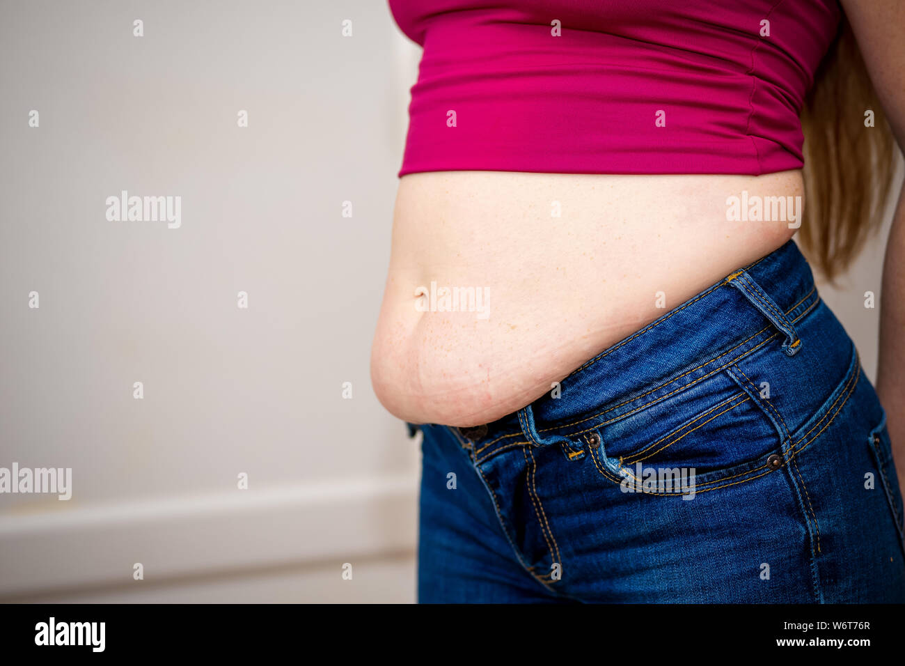Closeup of woman pinching belly fat. 