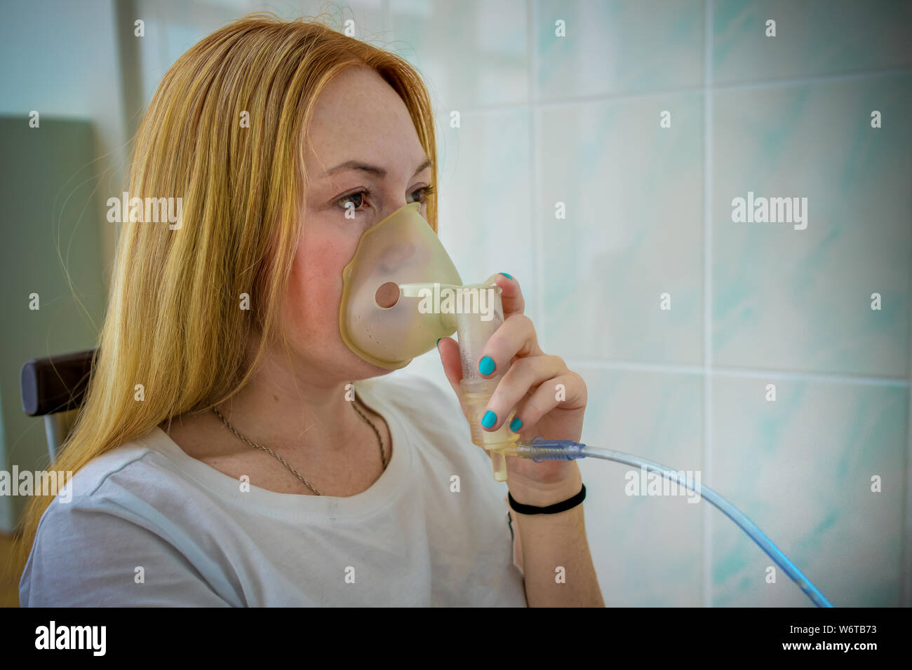 woman makes inhalation nebulizer at home. holding a mask nebulizer