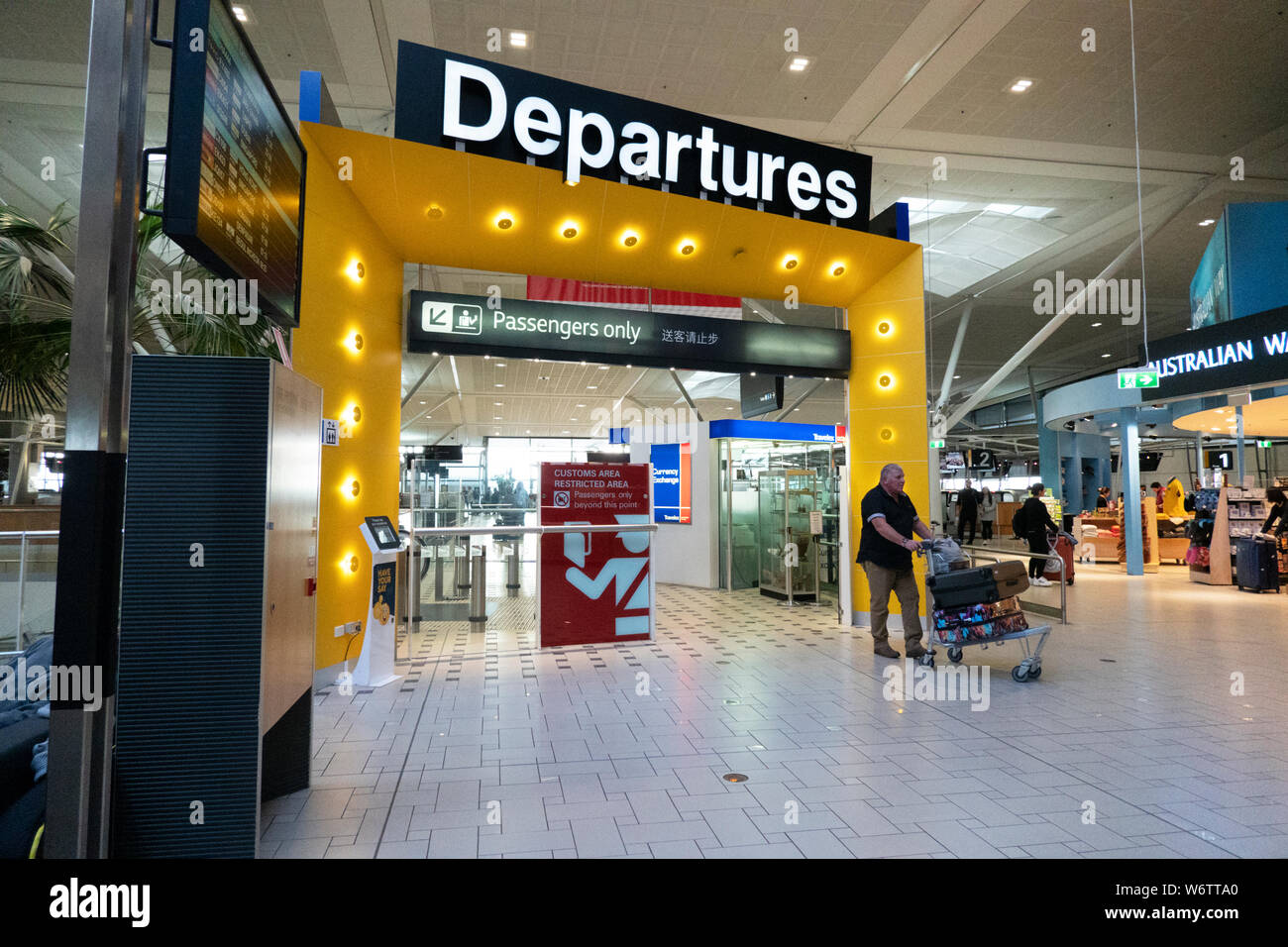 Travellers pushing a baggage trolley in front of departures gate at