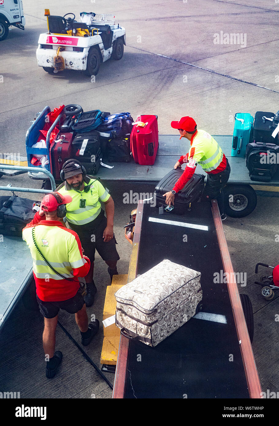 Baggage handlers unloading an aircraft at Brisbane airport, Queensland, QLD, Australia Stock Photo
