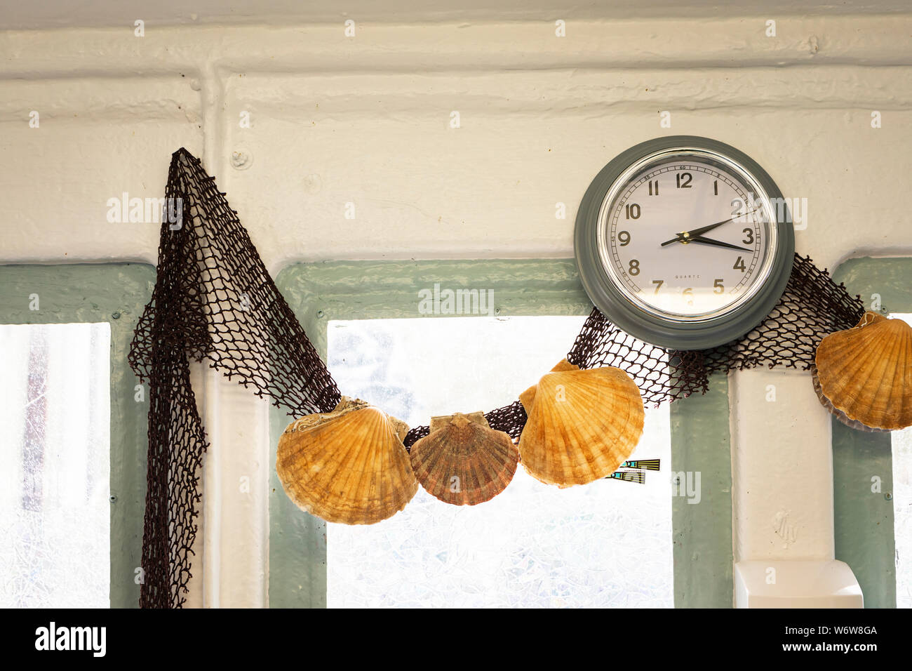 big scallop shells in a fishing net as a wall decoration Stock Photo