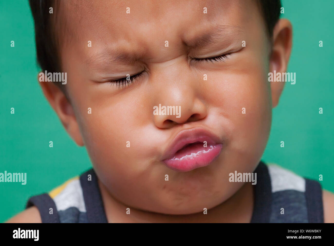 Young boy showing signs of distress with grimacing face. Stock Photo