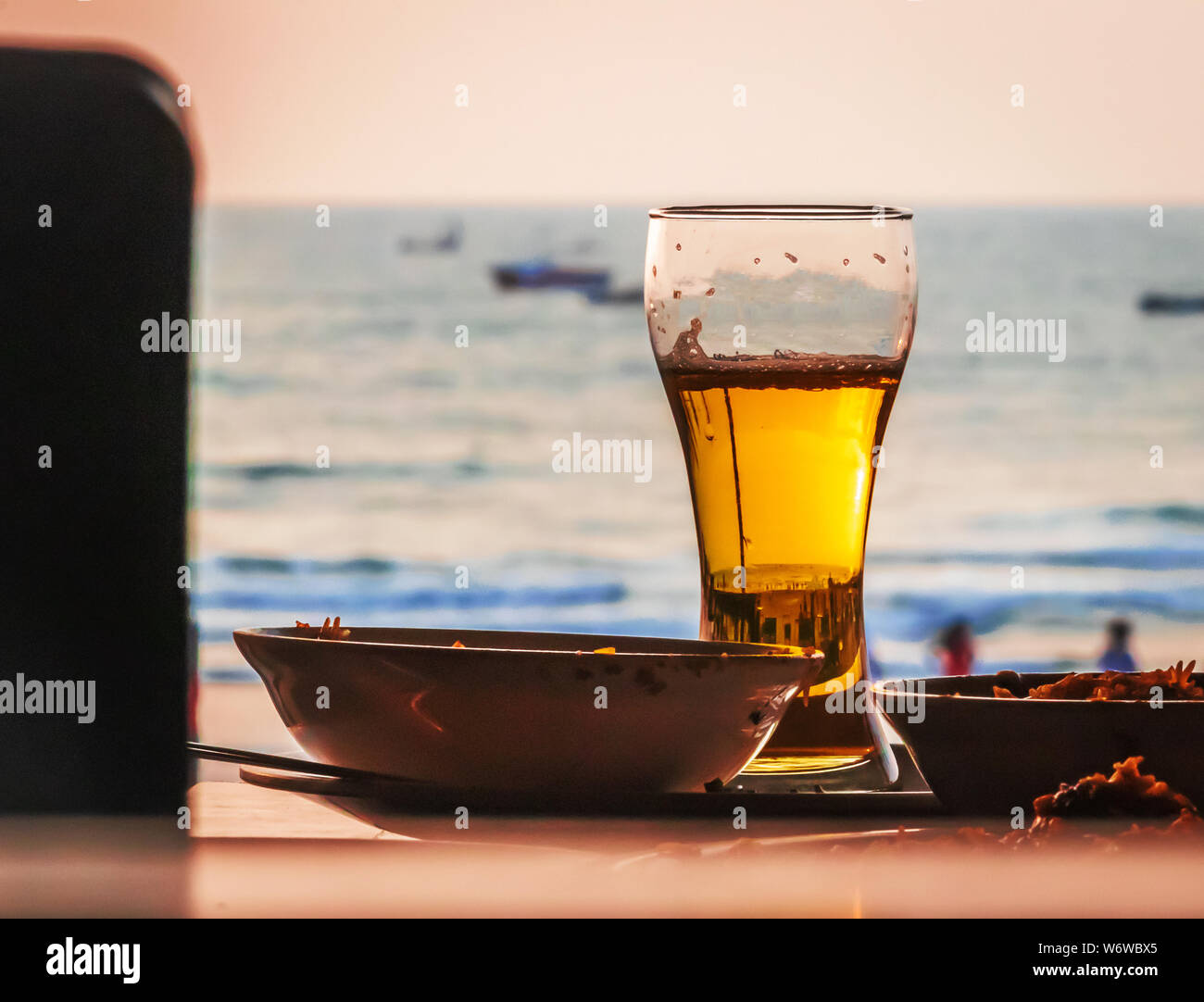 Cold beer on desk and background of summer beach with palm vagator beach Goa India Stock Photo