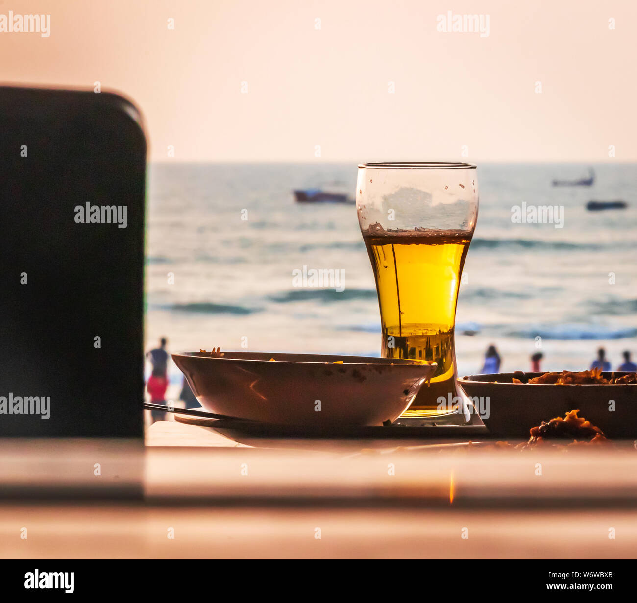 Cold beer on desk and background of summer beach with palm vagator beach Goa India Stock Photo