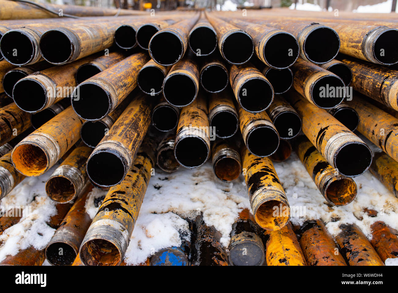 Salvaged pipes and casings are lined up on racks in storage on a ...