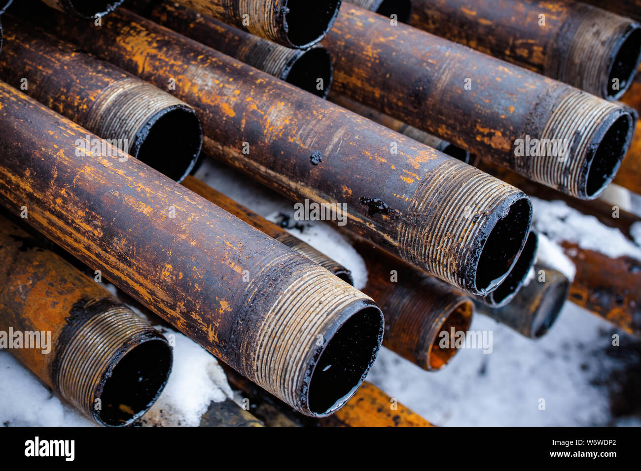 Salvaged pipes and casings are lined up on racks in storage on a ...