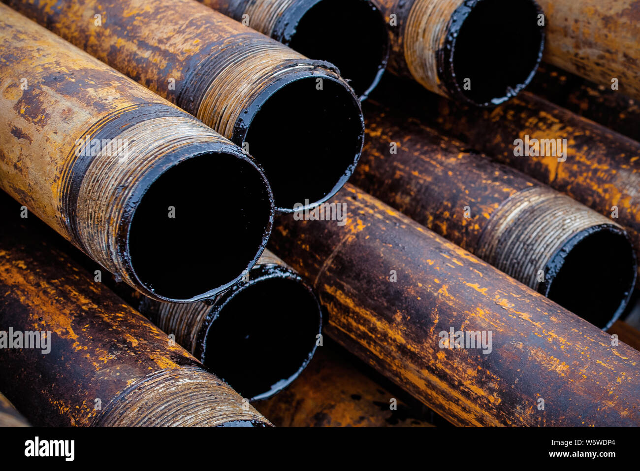 Salvaged pipes and casings are lined up on racks in storage on a ...
