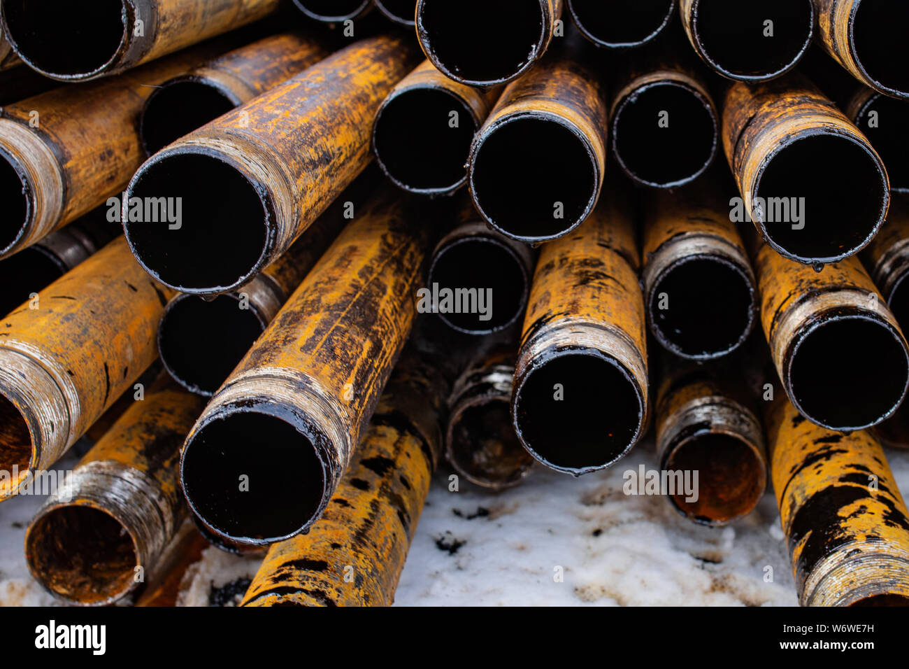 Salvaged pipes and casings are lined up on racks in storage on a ...