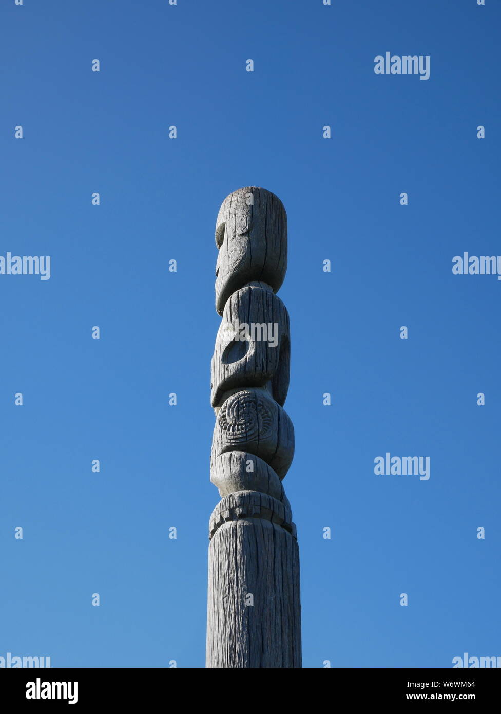Maori wooden sculpture in Whiteria Park, Porirua, against blue sky Stock Photo