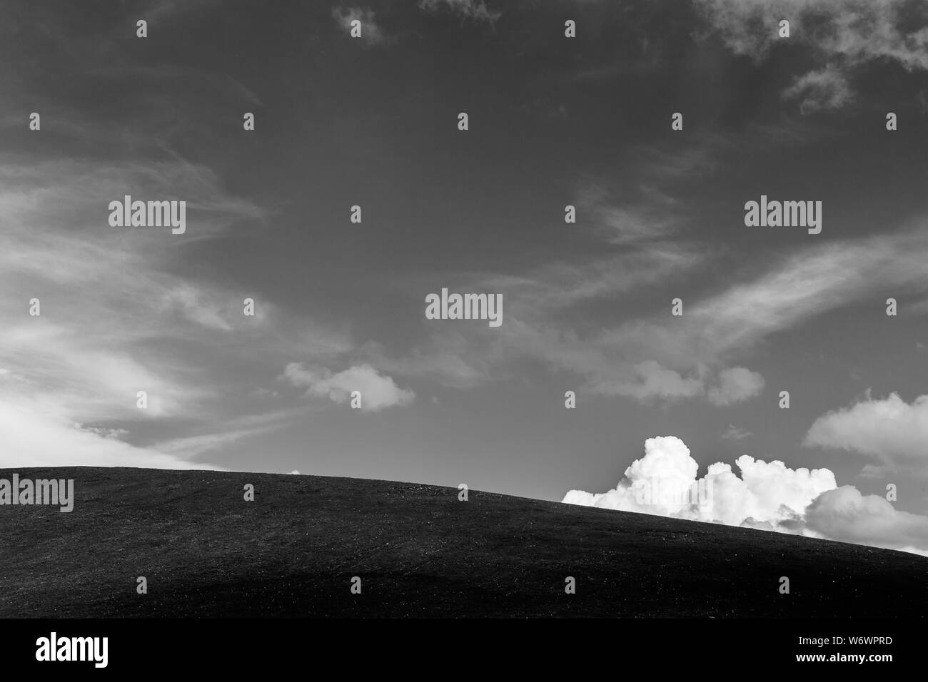 An hill top under a deep sky, with a white and fluffly cloud Stock Photo