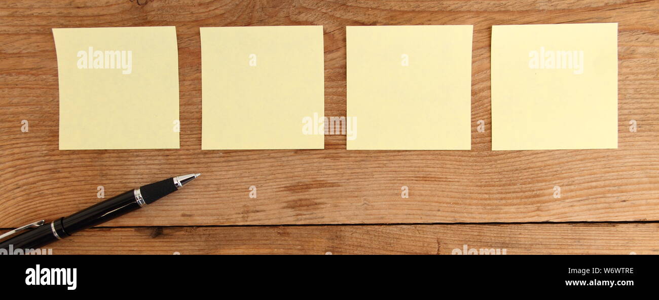 four yellow notes on a wooden table Stock Photo