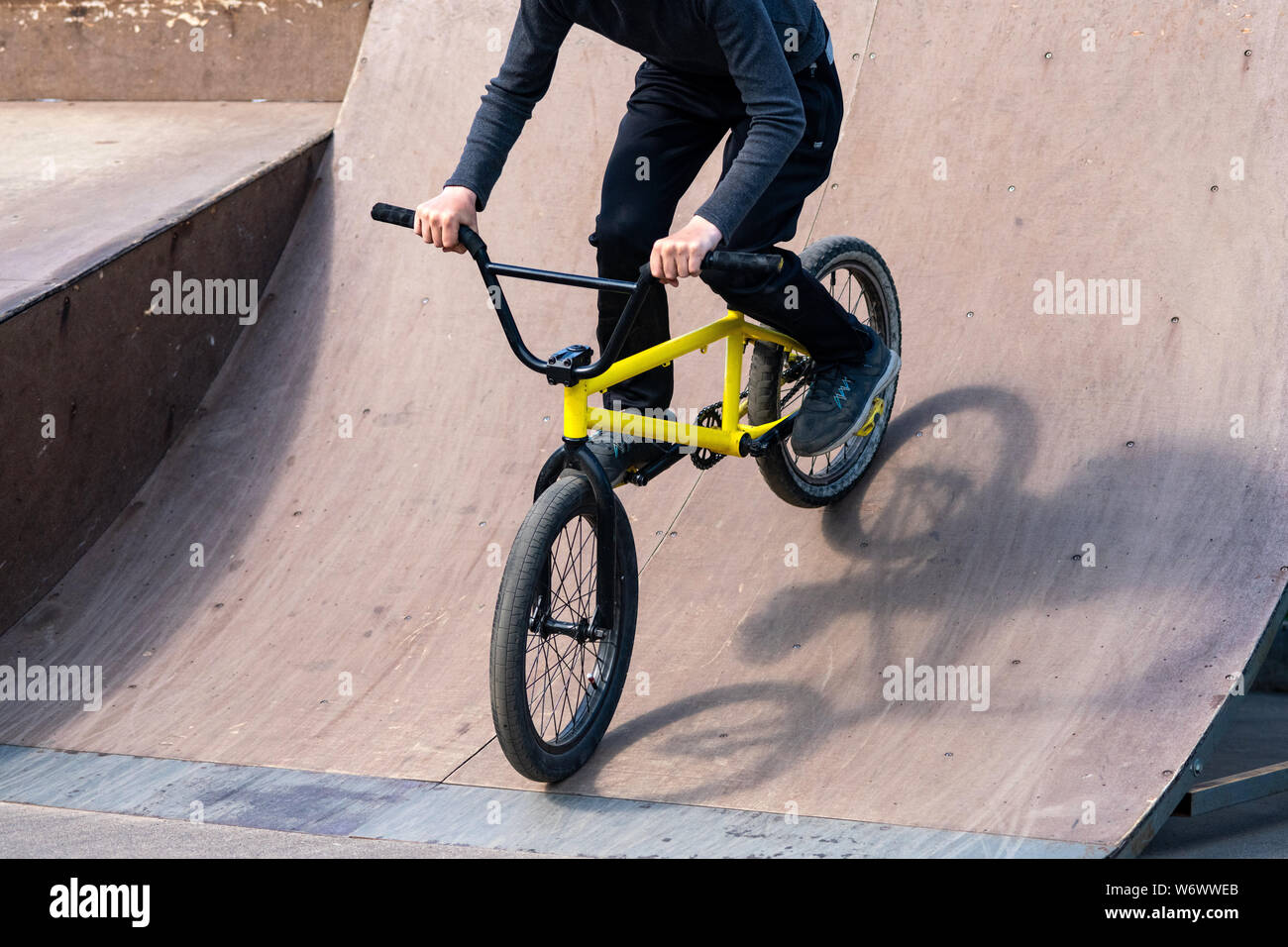 Young cyclist down the ramp. Guy is rolling down the bike from ramp ...