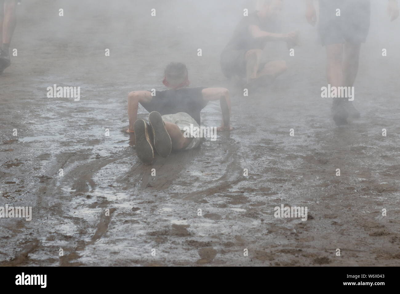 Kostrzyn, Polen, 2 August 2019, A young man slips over the mud.25. Pol'and'Rock Festival is the biggest non-commercial festival in Europe. This year the festival will take place on 1-3 August in the town of Kostrzyn nad Odra in western Poland. Stock Photo
