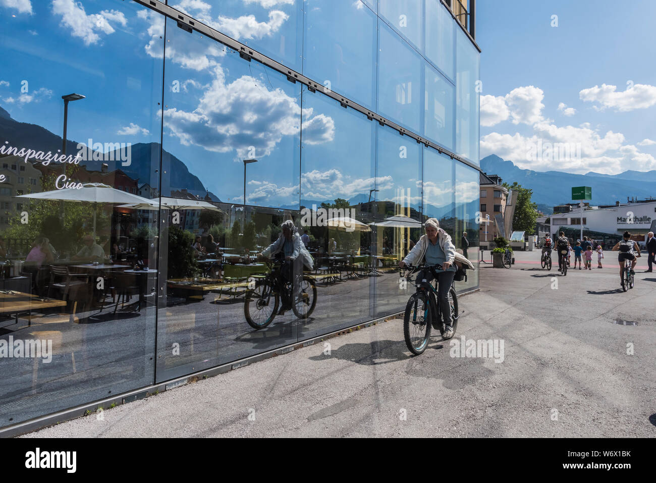 Window reflections of people enjoying themselves during a sunny summer day in the city Innsbruck provincial capitol city of the Tirol in Austria Stock Photo