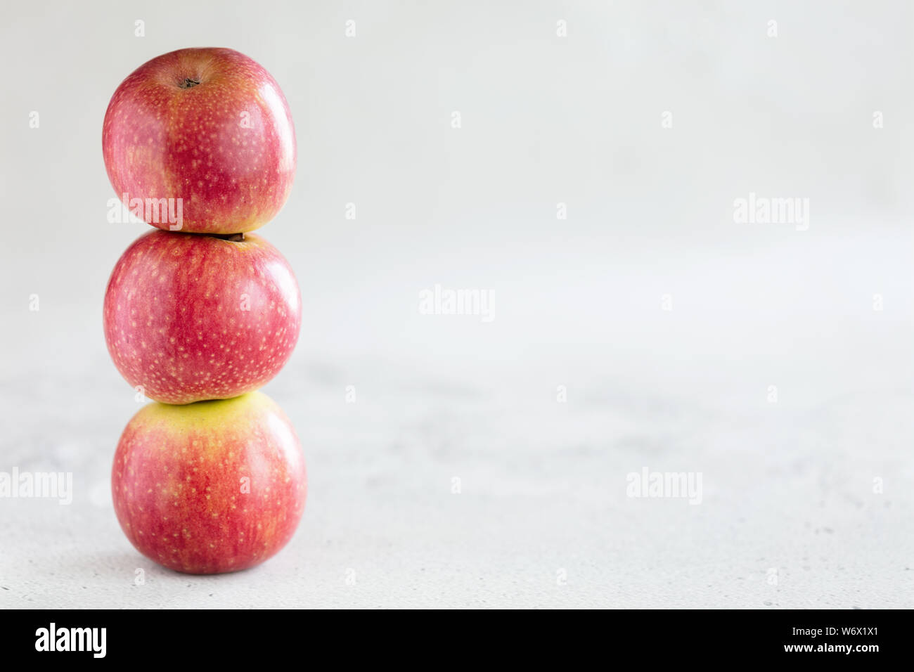 Stack of three apples on light gray background with copy space Stock Photo