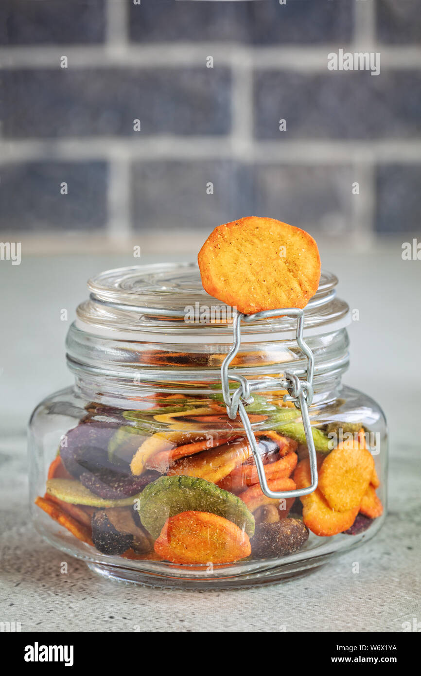 Colourful mix vegetable chips in glass jar, vertical composition Stock Photo