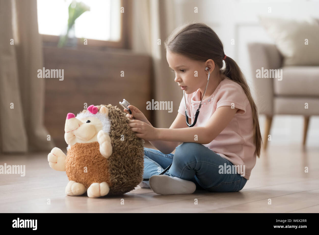 Little girl play doctor and treats hedgehog stuffed toy Stock Photo