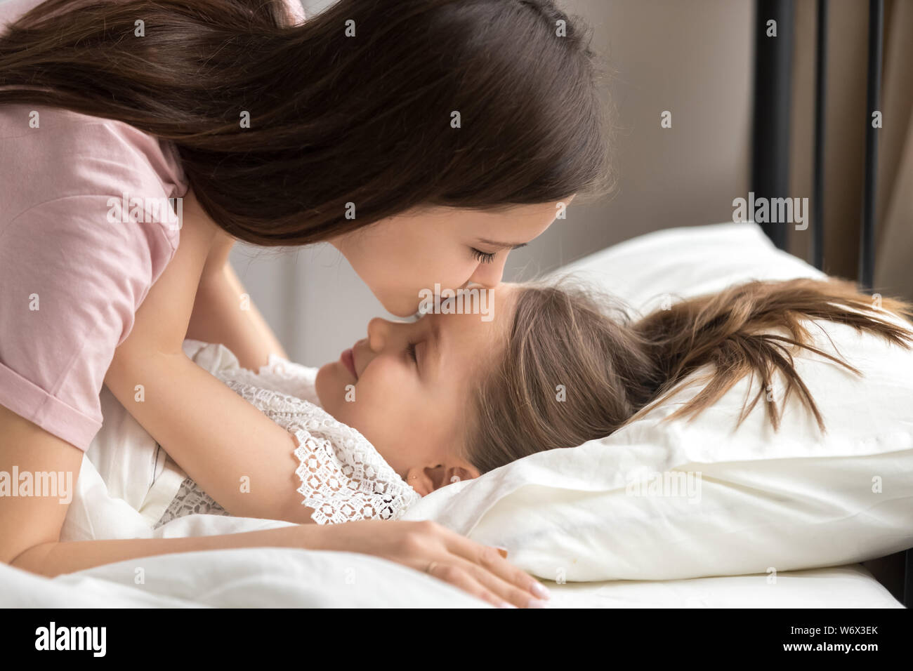 Mother kisses daughter puts to sleep in the afternoon nap Stock Photo