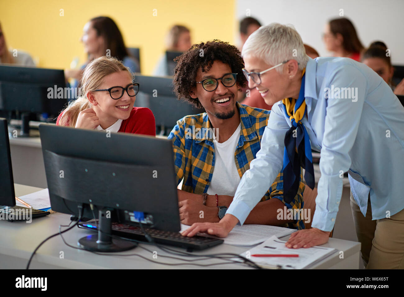 lecturer with group of smiling students working in computer class on ...