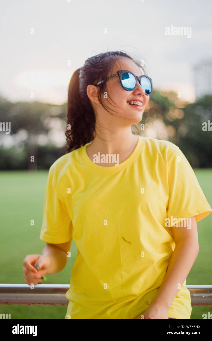 Lovely teen girl street style smiling with sunglasses under sunshine Stock Photo