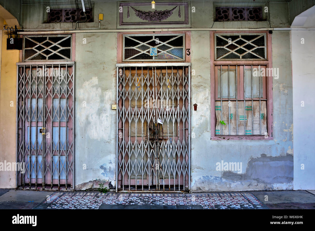 Entrance to traditional Peranakan shop house with brown and white antique door and windows on weathered wall in historic Geylang Singapore Stock Photo