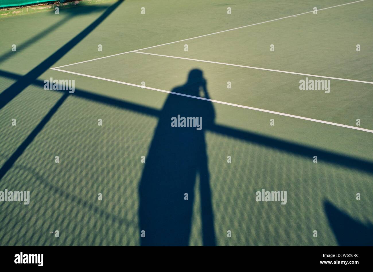 Shadow of a sportphotographer contrasting on a tennis court Stock Photo