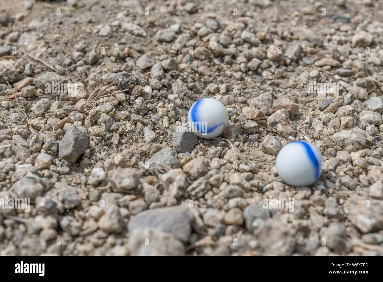 White glass marbles on gravel. Metaphor something lost, mental health, losing your marbles, childhood games, losing the plot, losing it. Stock Photo