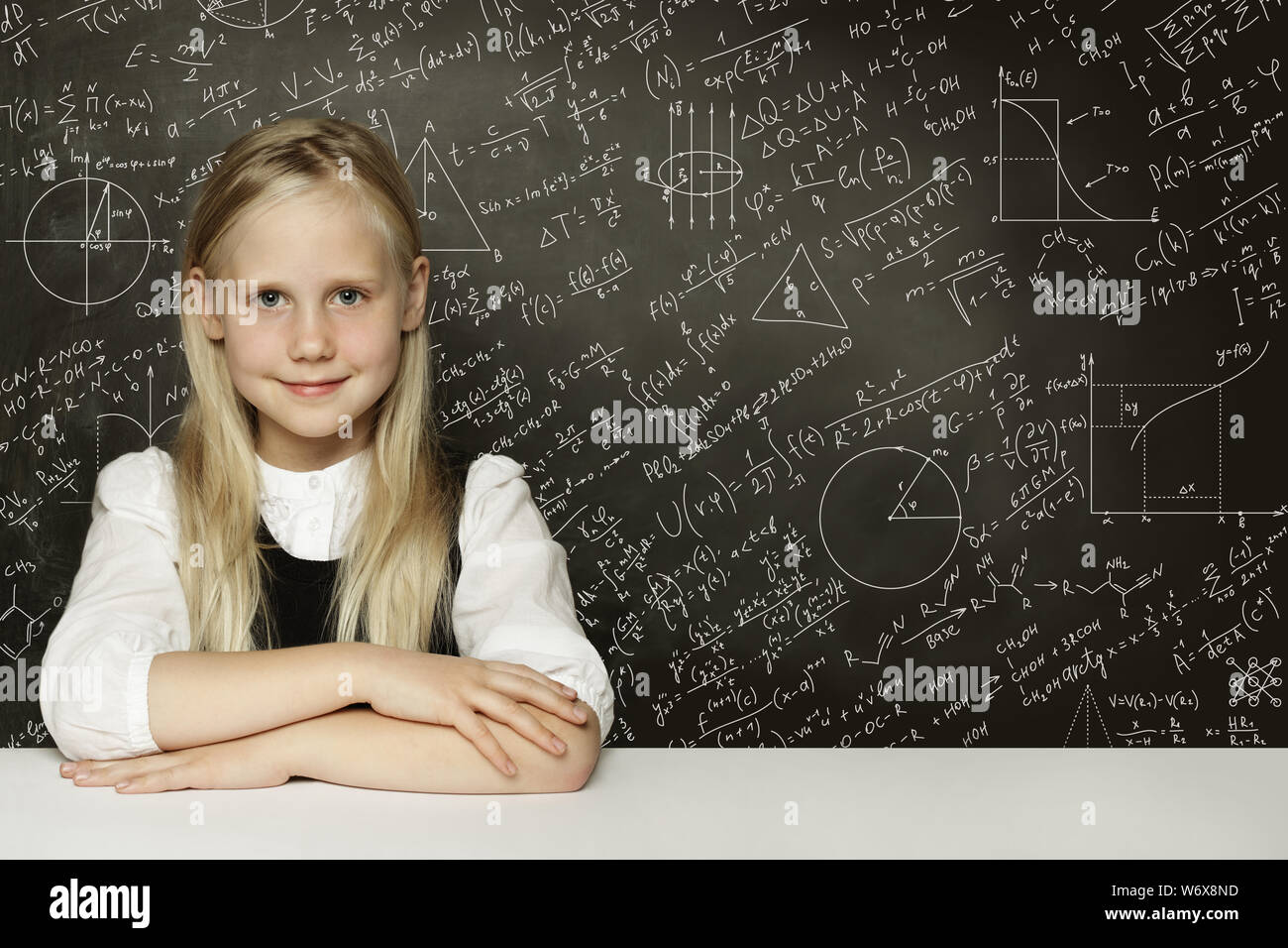 Cute smart child student girl on blackboard background with science formulas. Learning science concept. Stock Photo