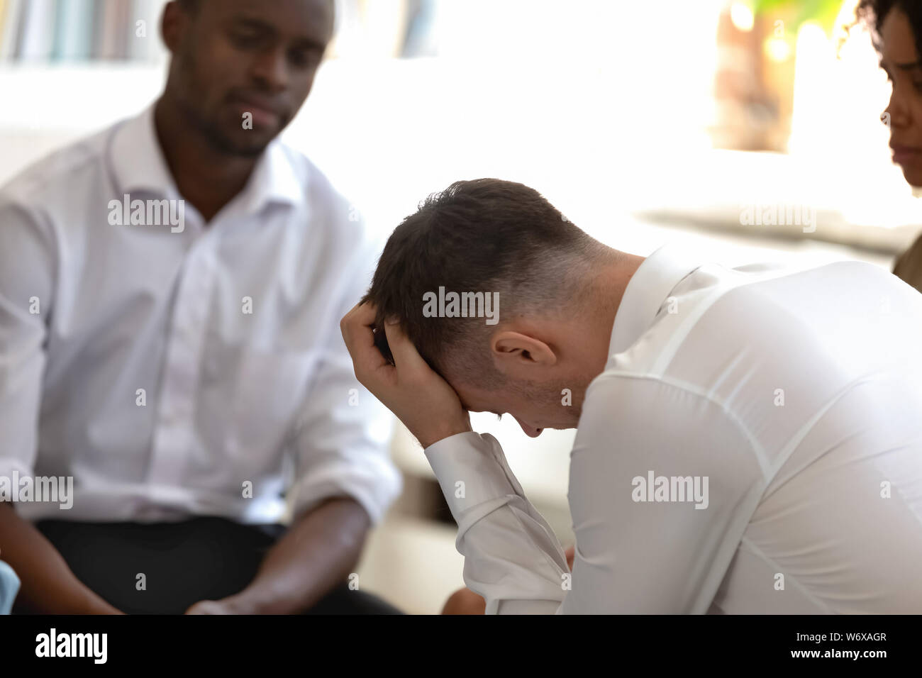 Diverse people during group therapy focus on desperate caucasian guy Stock Photo