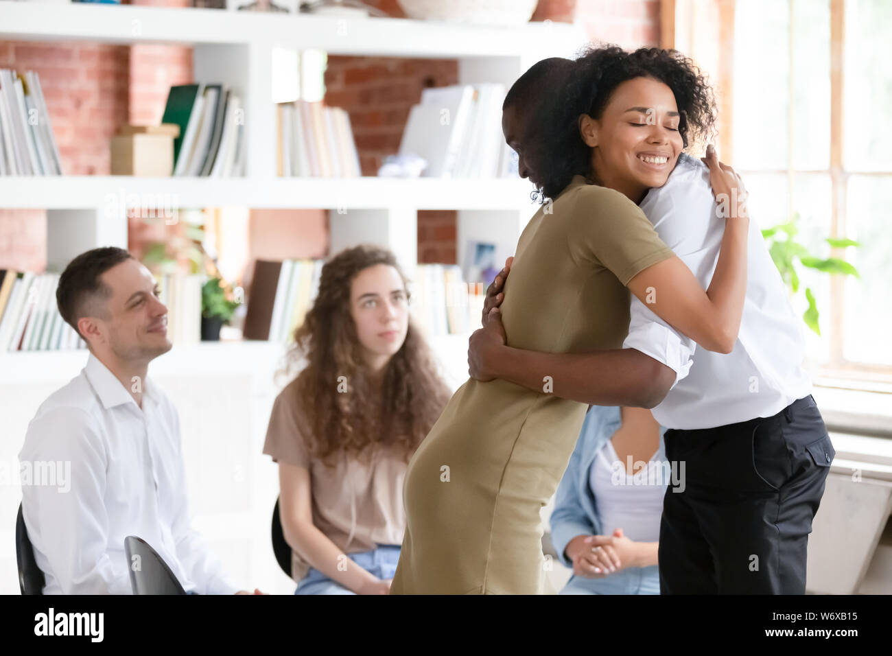 Woman psychologist addiction counsellor hugging supporting guy at group session Stock Photo