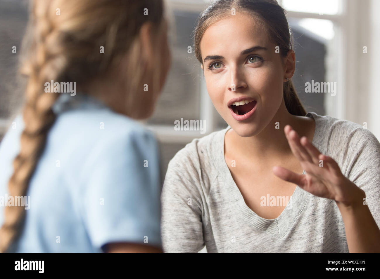 Young mother talking with daughter emotionally gesticulating using sign language Stock Photo