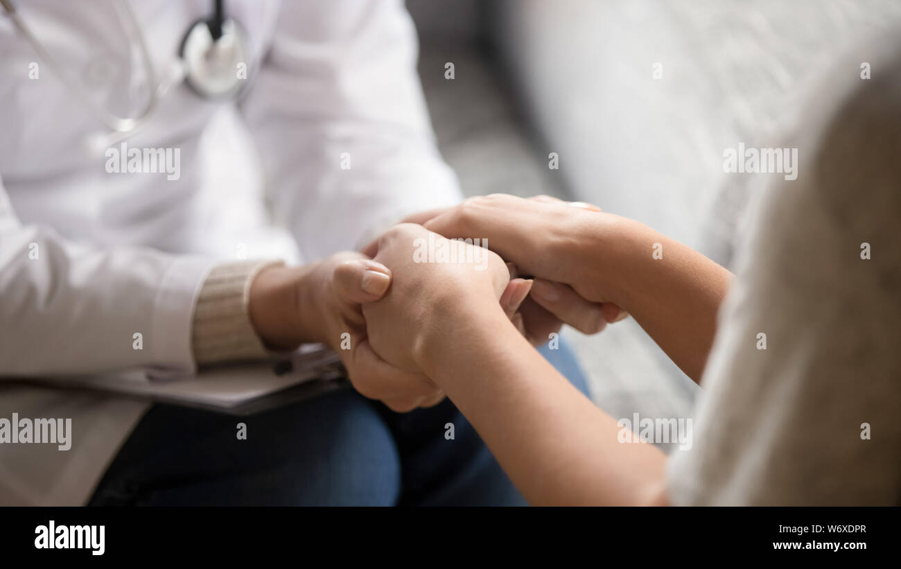Close up horizontal image doctor holding hands of female patient Stock Photo