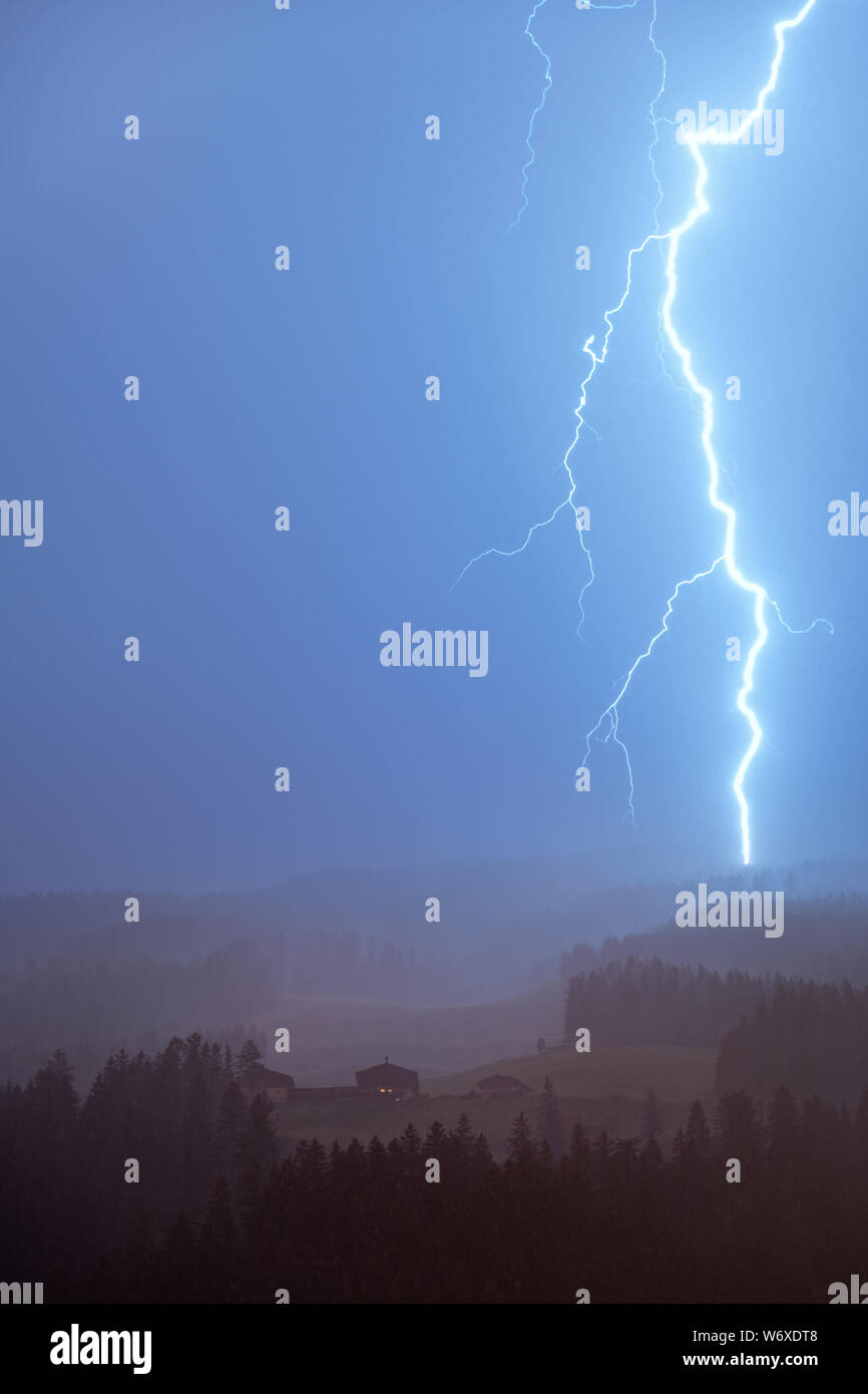 Lightning thunder storm over the cottage at summer night in Austria alps. Stock Photo
