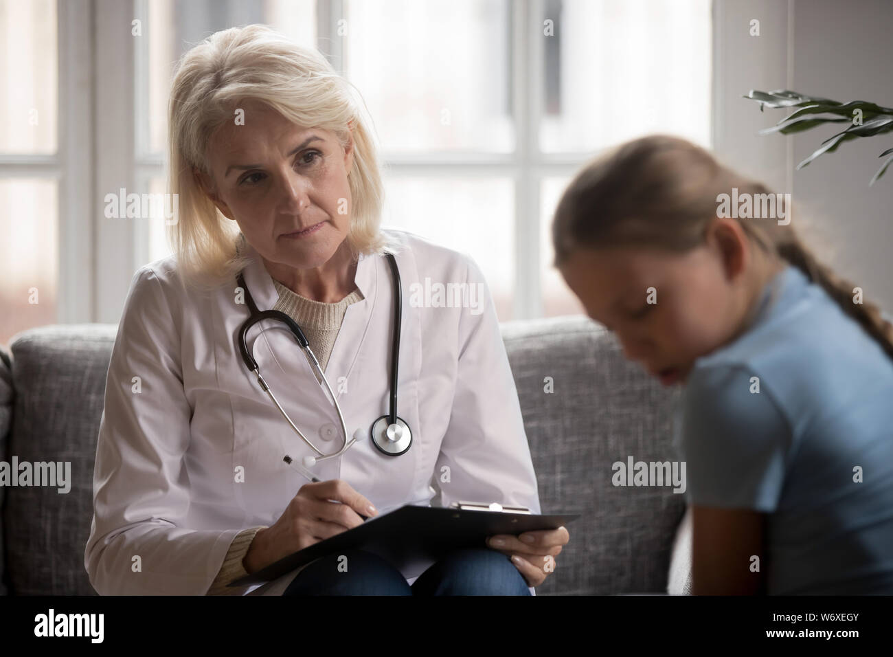 Scared closed child at appointment with general practitioner or psychologist Stock Photo