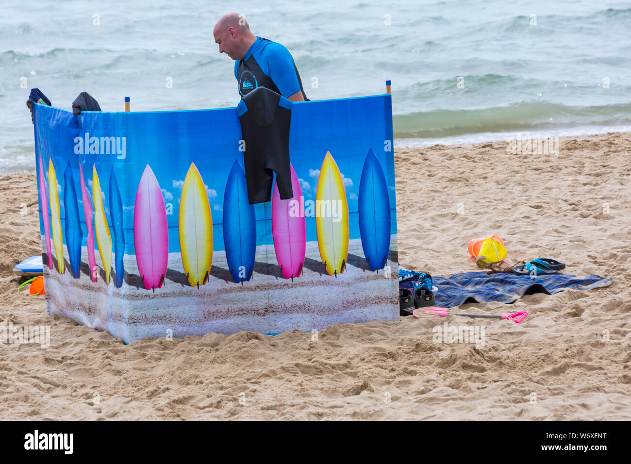Bournemouth, Dorset UK. 3rd Aug 2019. UK weather: overcast and cloudy, but warm and muggy. Beach goers head to the beaches at Bournemouth to enjoy the warm weather. Man behind windbreak wind break. Credit: Carolyn Jenkins/Alamy Live News Stock Photo