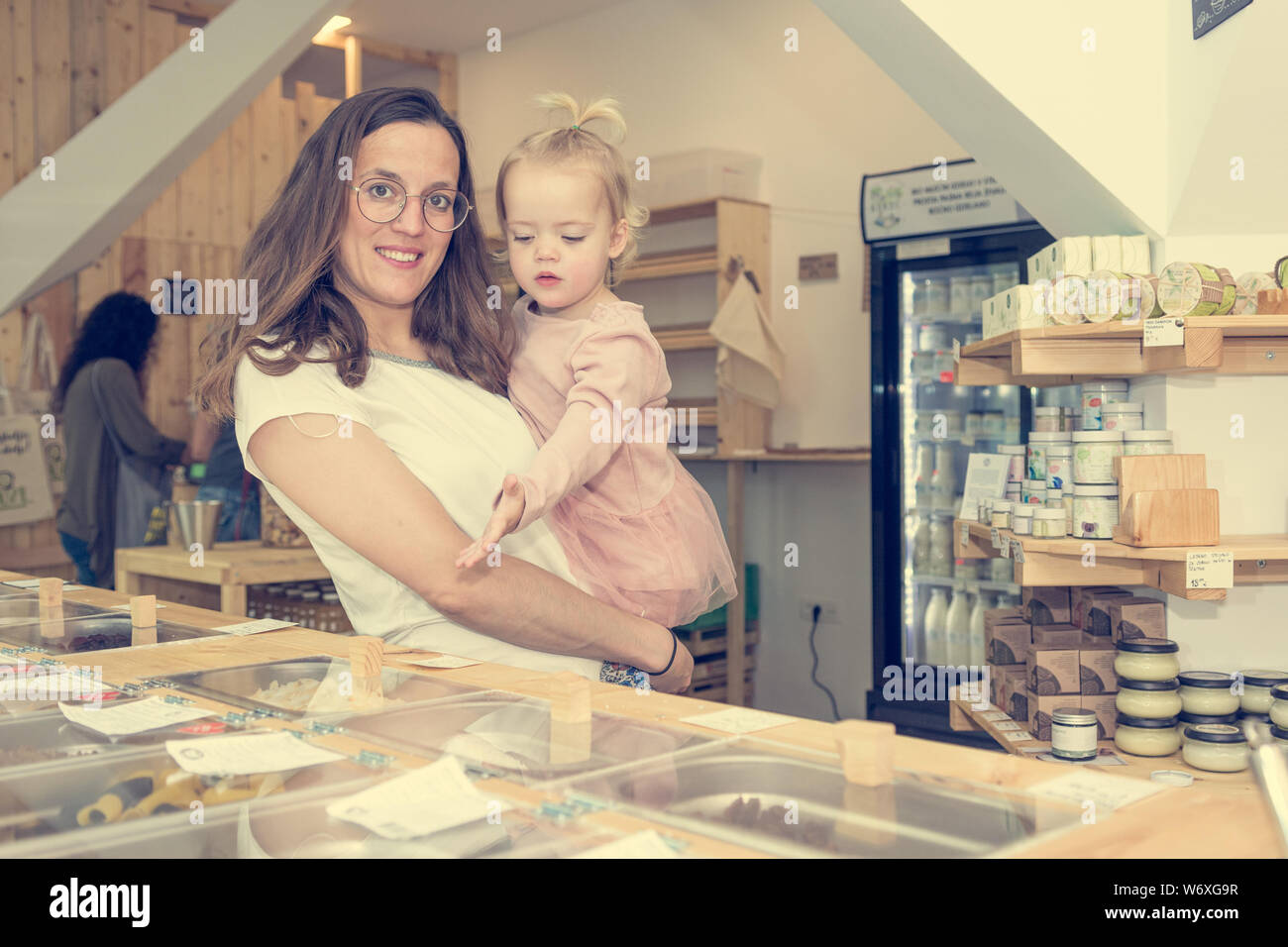 Young mother and daughter shopping in zero waste store. Stock Photo