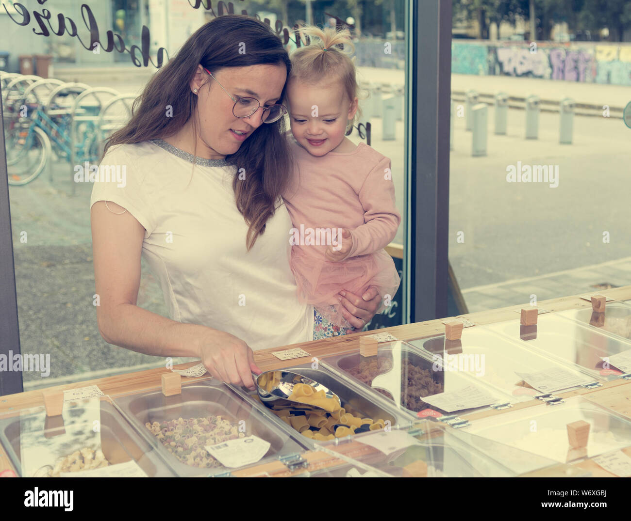 Young mother and daughter shopping in zero waste store. Stock Photo