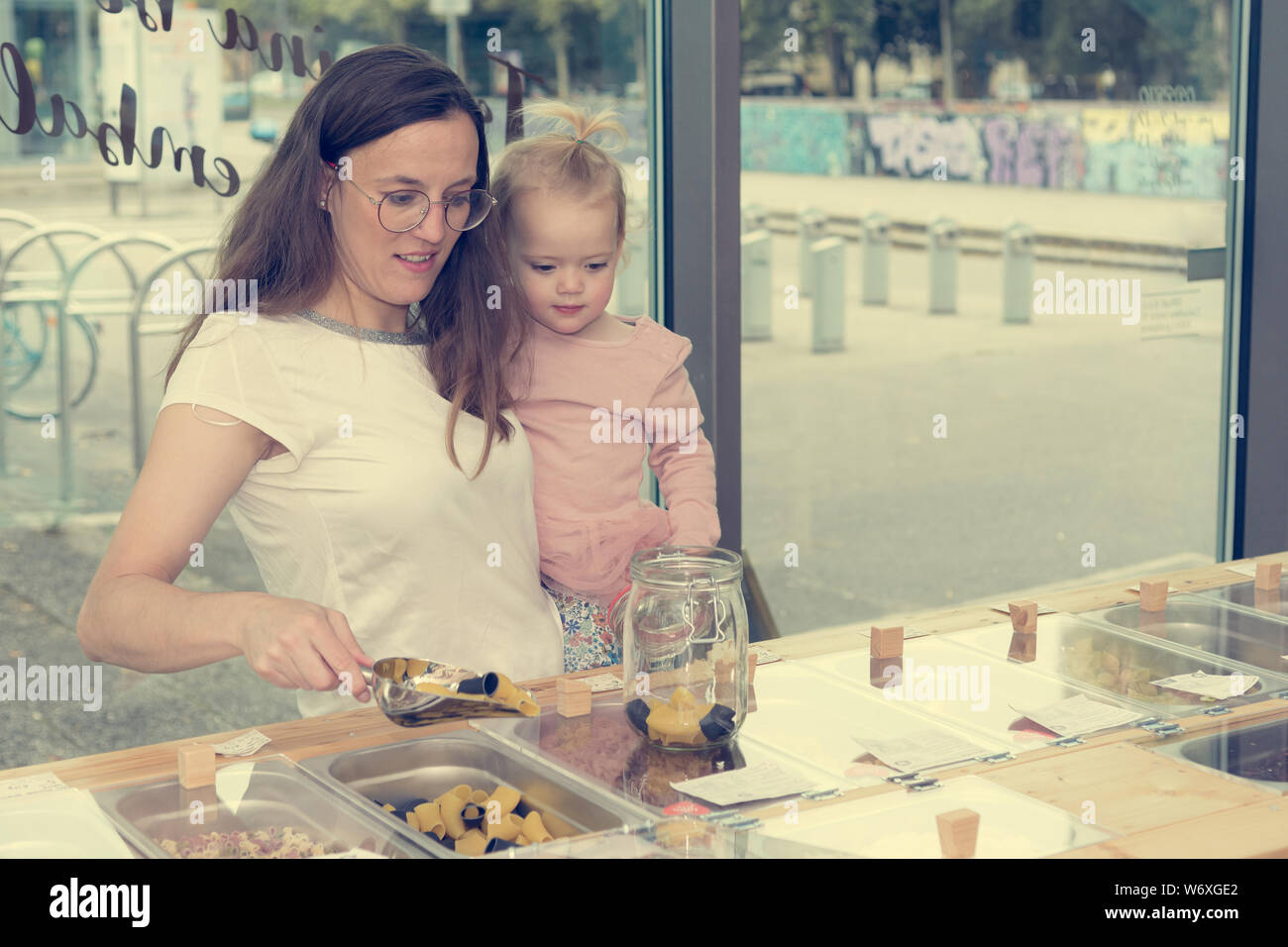 Young mother and daughter shopping in zero waste store. Stock Photo