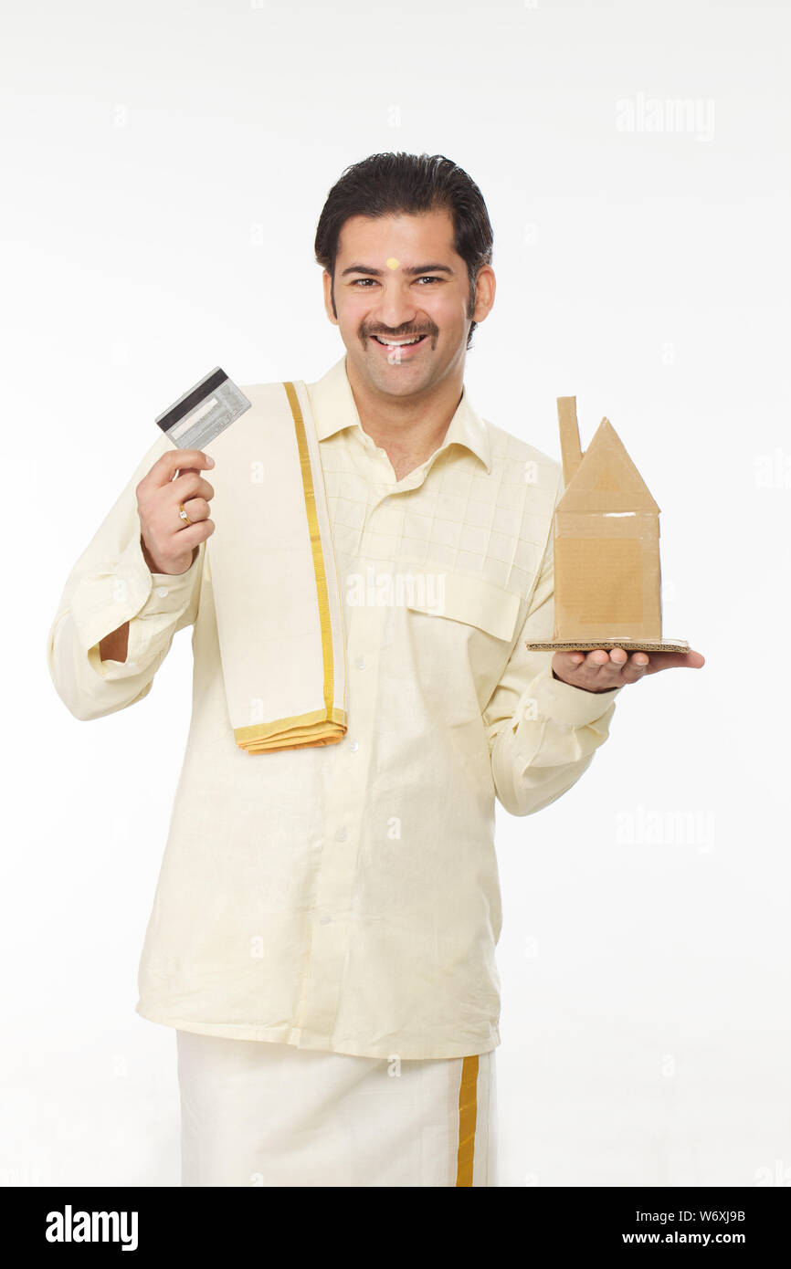 South Indian man showing a model of dream home and credit card Stock ...