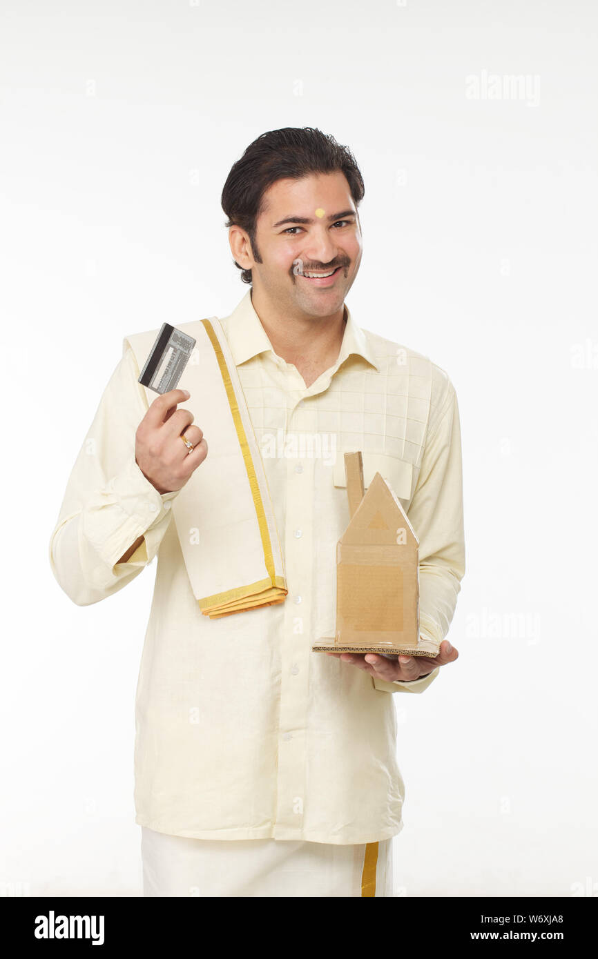 South Indian man showing a model of dream home and credit card Stock ...