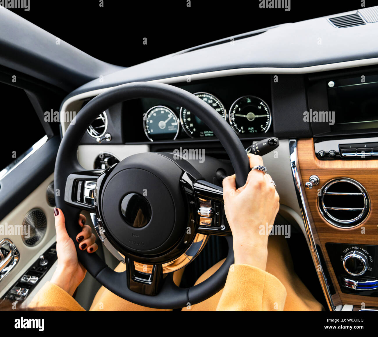 Woman's hands on the steering wheel driving modern luxury car. Concept