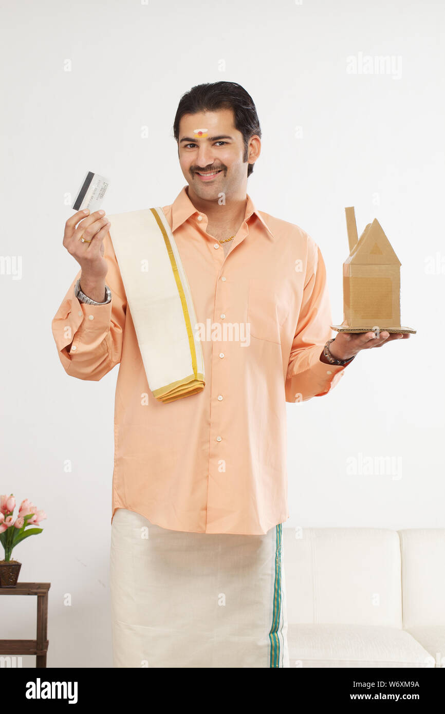 South Indian man showing a model of dream home and credit card Stock ...