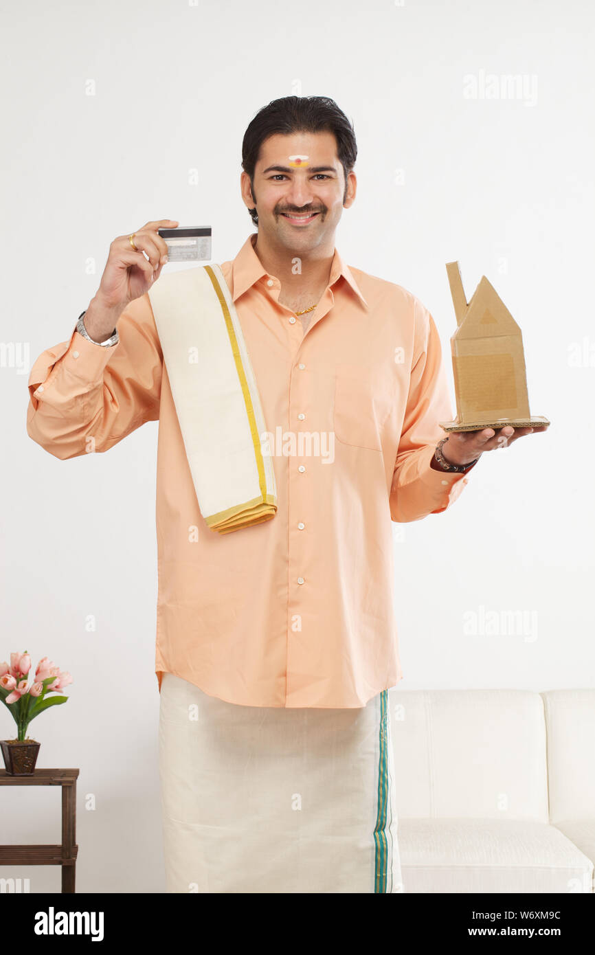 South Indian man showing a model of dream home and credit card Stock ...