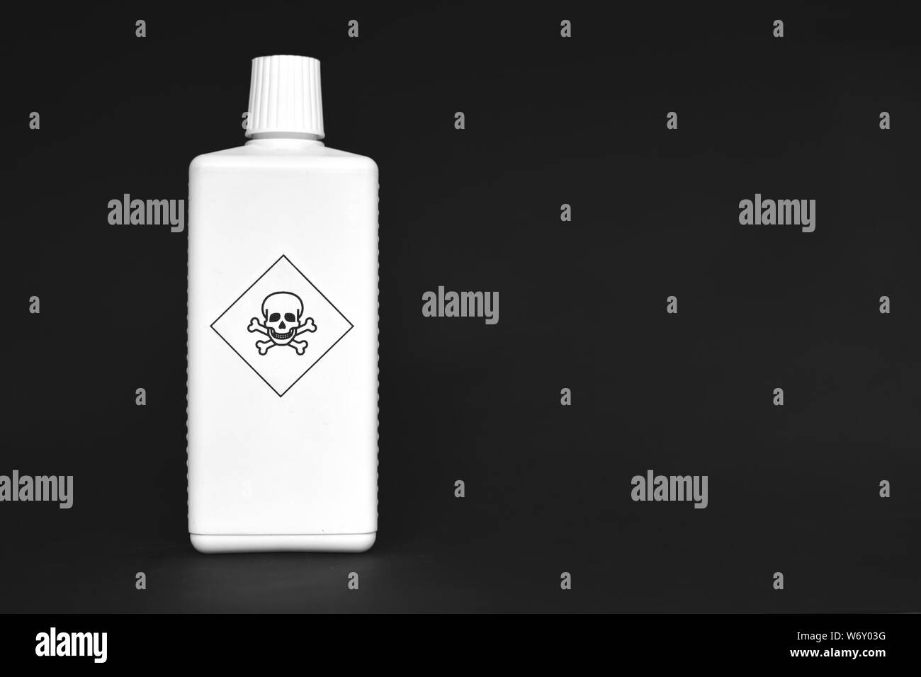 White bottle with poison warning signs on them on black background Stock Photo