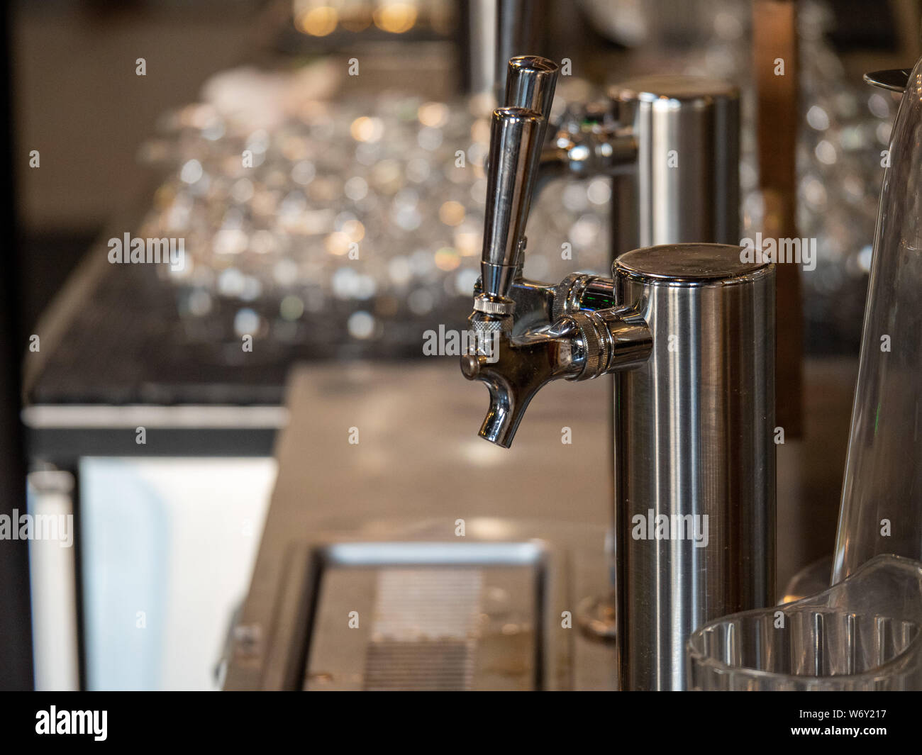 Silver beer taps behind bar counter tap next to clean glasses Stock