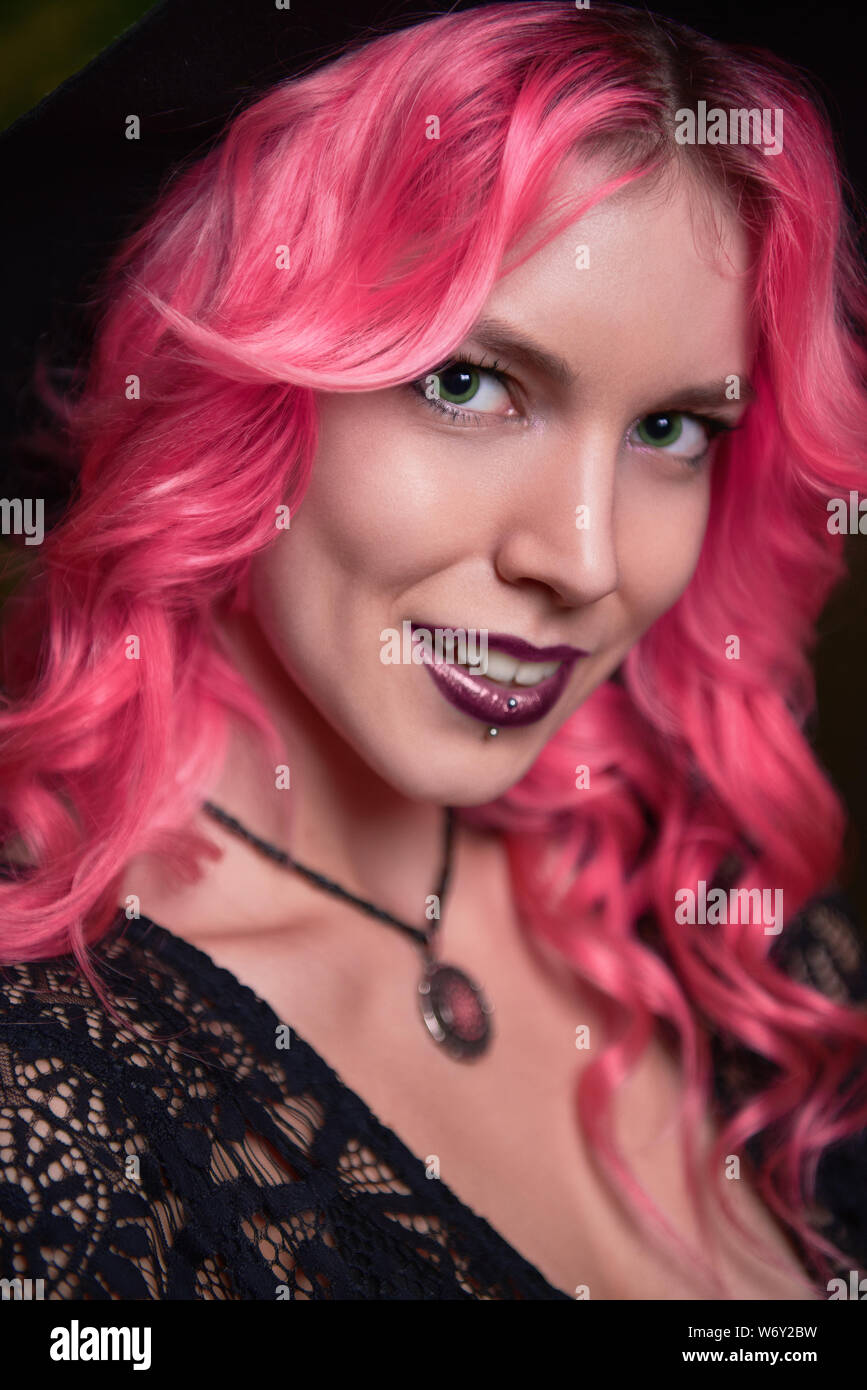 Beautiful young pink-haired witch. Close-up portrait of smiling young girl Stock Photo
